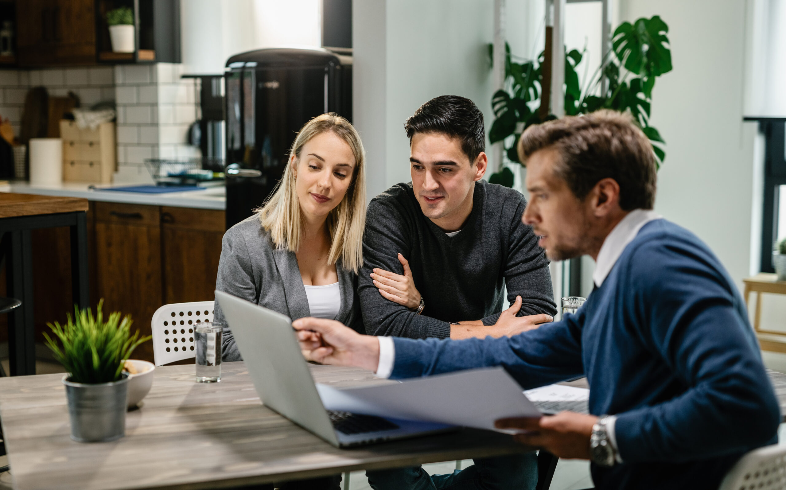 smiling couple using a computer with their investment agent on a meeting.
